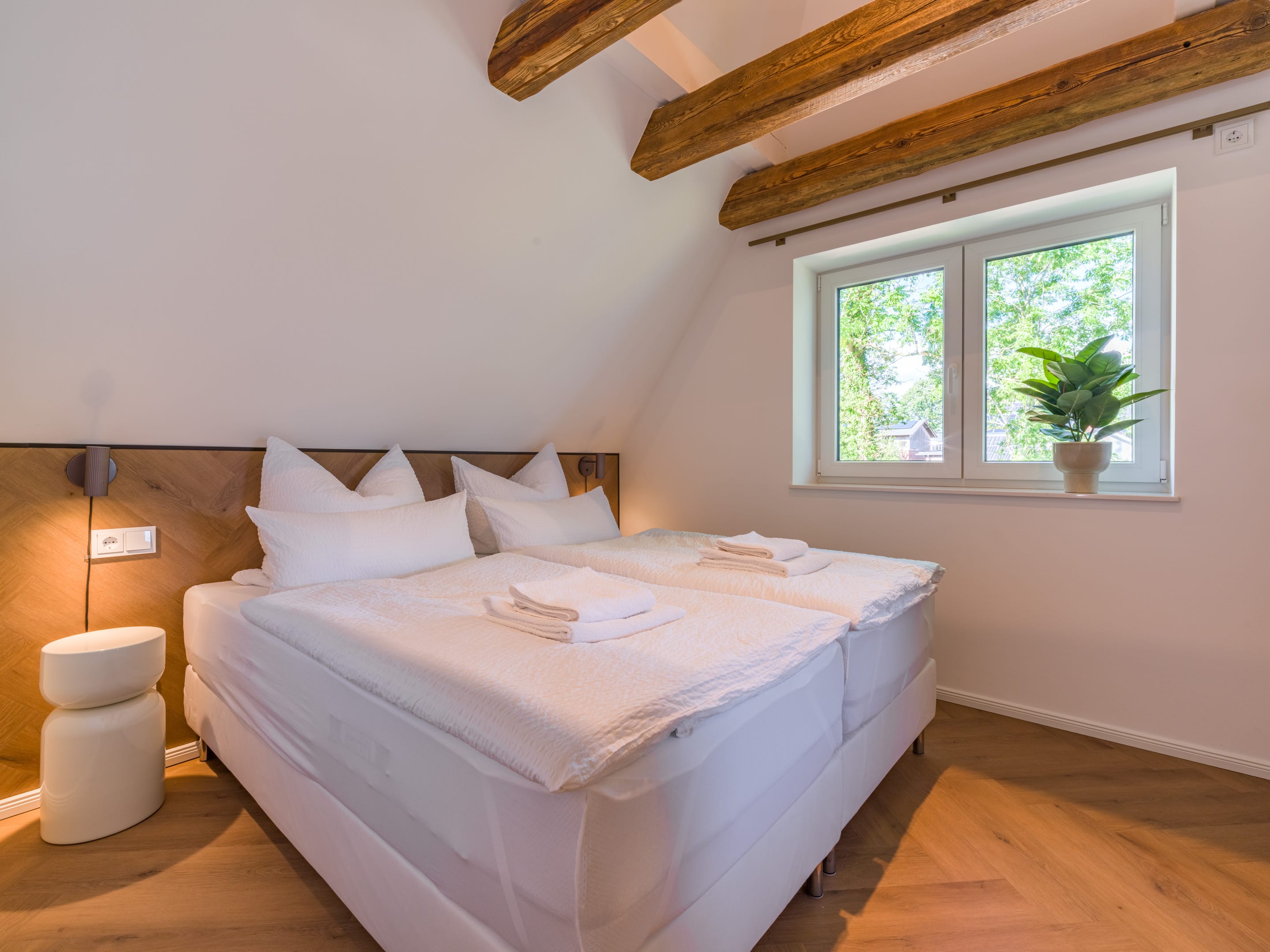 Schlafzimmer mit Doppelbett unter historischen Deckenbalken